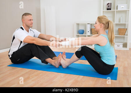 Young Couple Doing Exercise At Home On Blue Exercise Mat Stock Photo