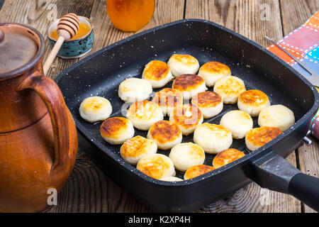 Sweet little fried cheesecakes in frying pan. Studio Photo Stock Photo
