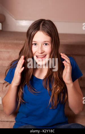 Excited girl wearing orthodontic braces with raised hands Stock Photo