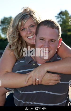 beautiful young engaged couple piggy back hug Stock Photo