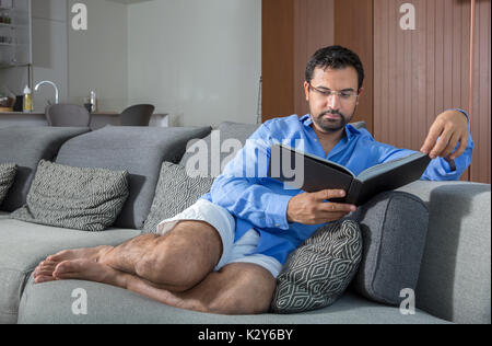 middle aged arab man reading a book in his city apartment Stock Photo
