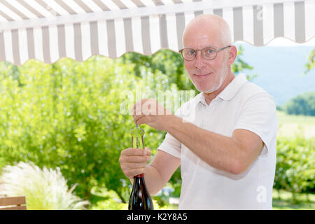 A mature man opening a bottle of red wine Stock Photo