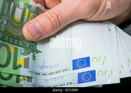 holding 100 euro money, hand holding one hundred euro cash isolated on a black background Stock Photo