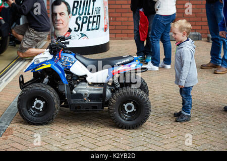 Small boy looks on at John McGuinness’ mini quad bike at the Manx Classic TT races, Isle of Man Stock Photo