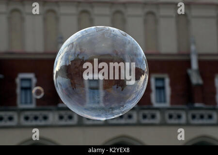 The buildings around the medieval square of Rynek Glowny in the Old Town of Krakow, Poland are reflected in a soap bubble created by a busker, photogr Stock Photo