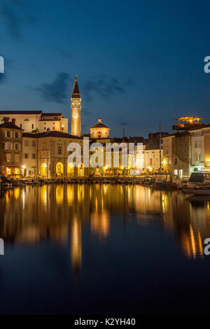 Piran, small and unique venetian town on the Slovenian coast with its little harbour in the warm summer evening and reflection in the coastal sea. Stock Photo