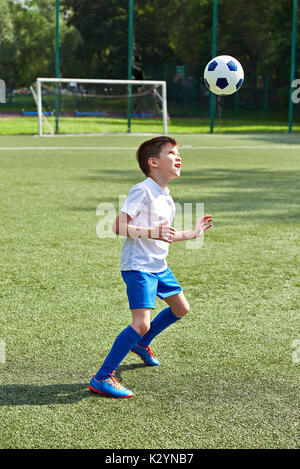 Boy soccer playing with ball on football stadium Stock Photo