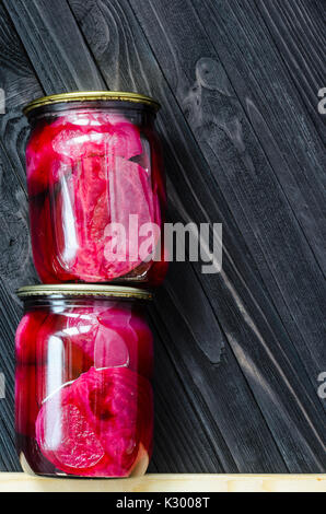 Two cans of canned beets standing on top of each other on a black wooden background with copy space for your text message top vew Stock Photo
