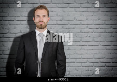 Handsome elegant businessman in suit copy space, gray brick wall in background Stock Photo
