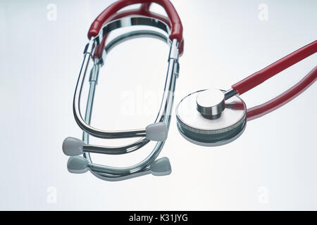Red color stethoscope with reflection on glossy background. Stock Photo