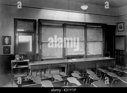 Sepia photograph of a third floor graduate lecture room inside the Chemistry Building at Old Campus Johns Hopkins University, showing rows of empty auditorium style desks facing the front of the classroom, with a blackboard covered in Organic Chemistry problems, Baltimore, Maryland, 1918. Stock Photo