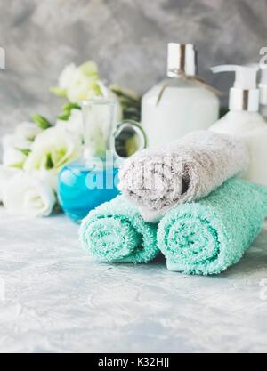 Spa set on a white marble table with a stack of towels, colors, accessories, and bath with sea salt and aromatic oil, selective focus Stock Photo