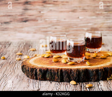 Italian liqueur Amaretto in cups with almonds on a wooden table, selective focus Stock Photo