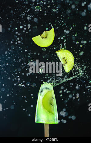 Popsicle with fresh cherries on a dark background, dynamic shot with action, splash, water drops and bokeh. Melting ice cream still life with floating Stock Photo