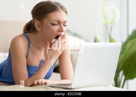 Tired woman yawning after too long work on laptop Stock Photo