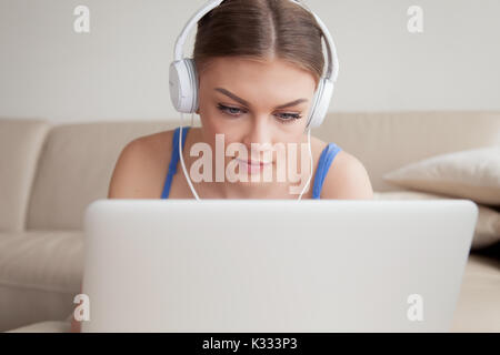 Woman in headphones using laptop at home Stock Photo