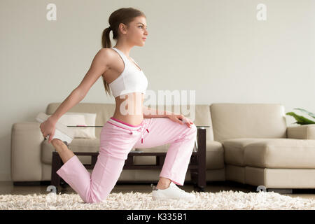 Young woman doing quad stretches at home Stock Photo