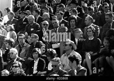 Milton Stover Eisenhower (center, in sunglasses), President of Johns Hopkins University, talks to his nephew (to his left) surrounded by spectators on stands at a Hopkins lacrosse game, in Baltimore, Maryland, April 6, 1963. Stock Photo