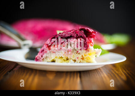 layered pastry salad with herring and beetroot on a wooden table Stock Photo