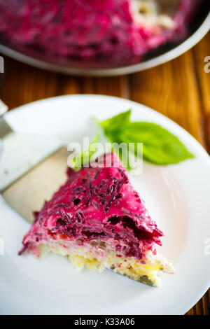 layered pastry salad with herring and beetroot on a wooden table Stock Photo