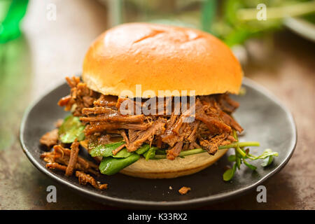 Sweet bun barbecue beef brisket with watercress leaves. Whisky barrel chip smoked British beef brisket with smoky barbecue sauce Stock Photo