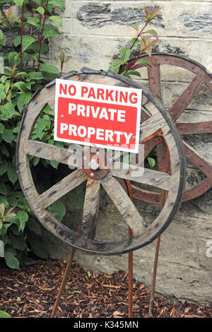 No Parking, Private Property sign mounted on old wooden cart wheels Stock Photo