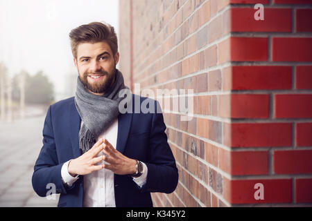 A photo of young man wearing navy suit and shawl. He's smiling confidently. Stock Photo