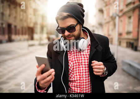 A photo of young, trendy man checking the messages on his mobile. Stock Photo