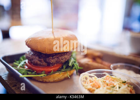 A photo of hamburger pierced by a long toothpick and a salad next to it. Stock Photo