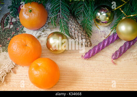 On a wooden table beautifully set decorations and gifts for Christmas, the New year pine branches, cones, shiny balls, candles, confetti. Stock Photo