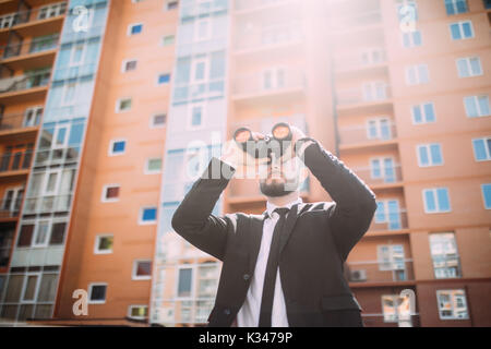 Handsome Businessman with binoculars spying on competitors Stock Photo