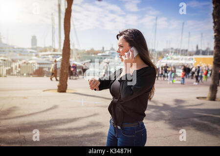 A photo of young woman waiting for someone on the boulevard at the resort. She's talking on the mobile. Stock Photo