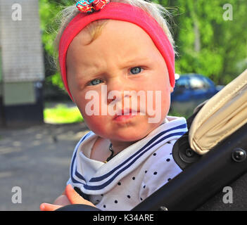 Little baby girl sitting in the baby stroller outdoors Stock Photo