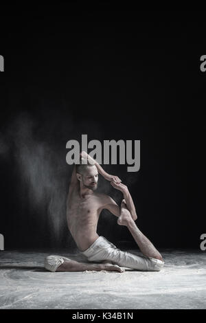 Sporty muscular young yogi man doing variation of One Legged Royal Pigeon Pose, Eka Pada Rajakapotasana Stock Photo