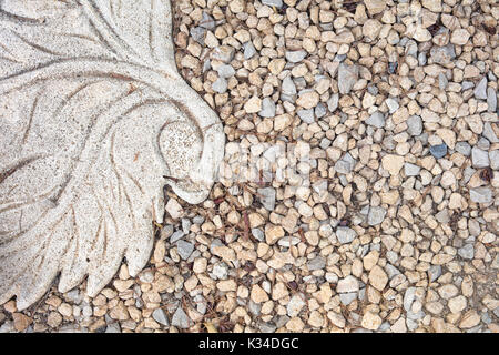 View of gravel and part of stone tile with leaf form as decoration. Stock Photo