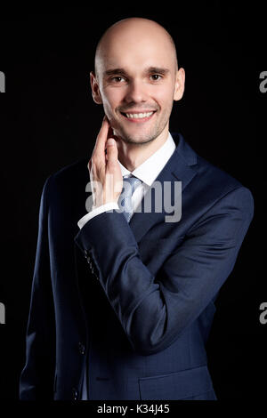 Smiling man stroking his chin. Studio shot on black background. Stock Photo