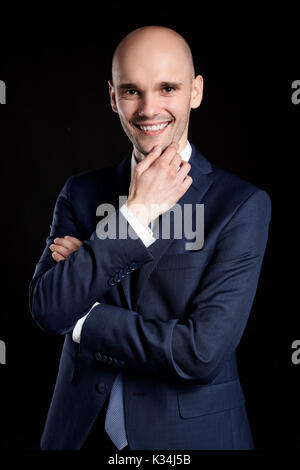 Smiling man stroking his chin. Studio shot on black background. Stock Photo