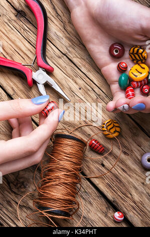 Female hands with colored beads necklace manufacturing Stock Photo