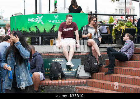 LONDON, ENGLAND - August 11 2017 A motley crowd sits outside the pub, drinks beer, talks with friends. Southbank Stock Photo