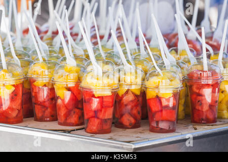 Sliced fresh fruits sorted in plastic cups with forks. Street dessert shop in Lisbon, Portugal. Close-up photo with selective focus Stock Photo