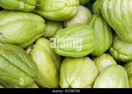 Green Chayote fruits lay on the counter of street food market on Madeira island, Portugal. Close-up photo with selective focus Stock Photo