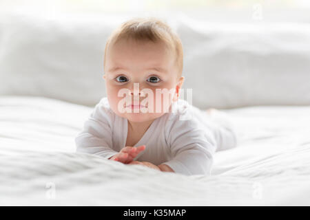 Cute happy 7 month baby girl in diaper lying and playing Stock Photo