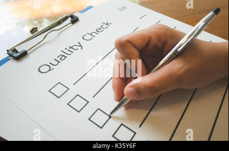 Close- up hand holding pen on quality check paper and the format for filling in information in business concept,vintage style and softtone Stock Photo