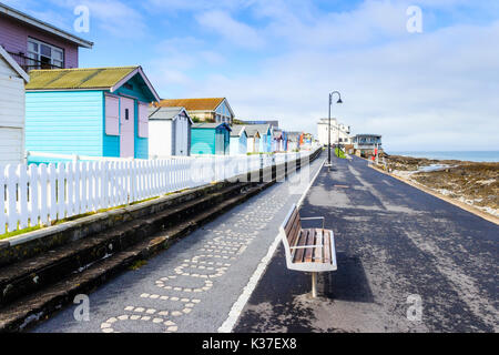 Turquoise blue painted beach huts and white picket fence on the promenade at Westward Ho!, Devon, England, UK Stock Photo
