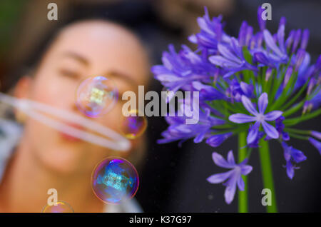 Blurred woman playing with soap bubbles on a summer nature, in a blurred nature background Stock Photo