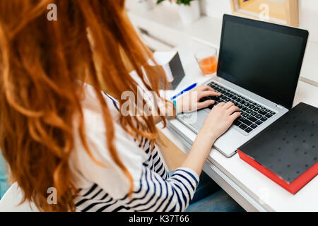 Red haired woman working on laptop Stock Photo