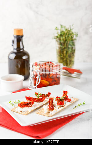 Crispbread with soft ricotta cheese and sun-dried tomatoes and thyme Stock Photo