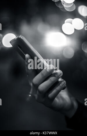 A hand holding and using digital smart phone at night. Stock Photo