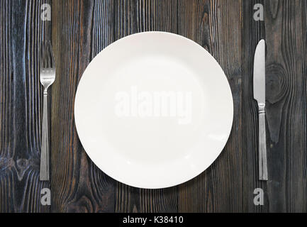 white plate, knife, fork, on a background of wood Stock Photo