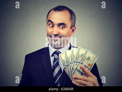 Funny sly business man holding looking at money Stock Photo